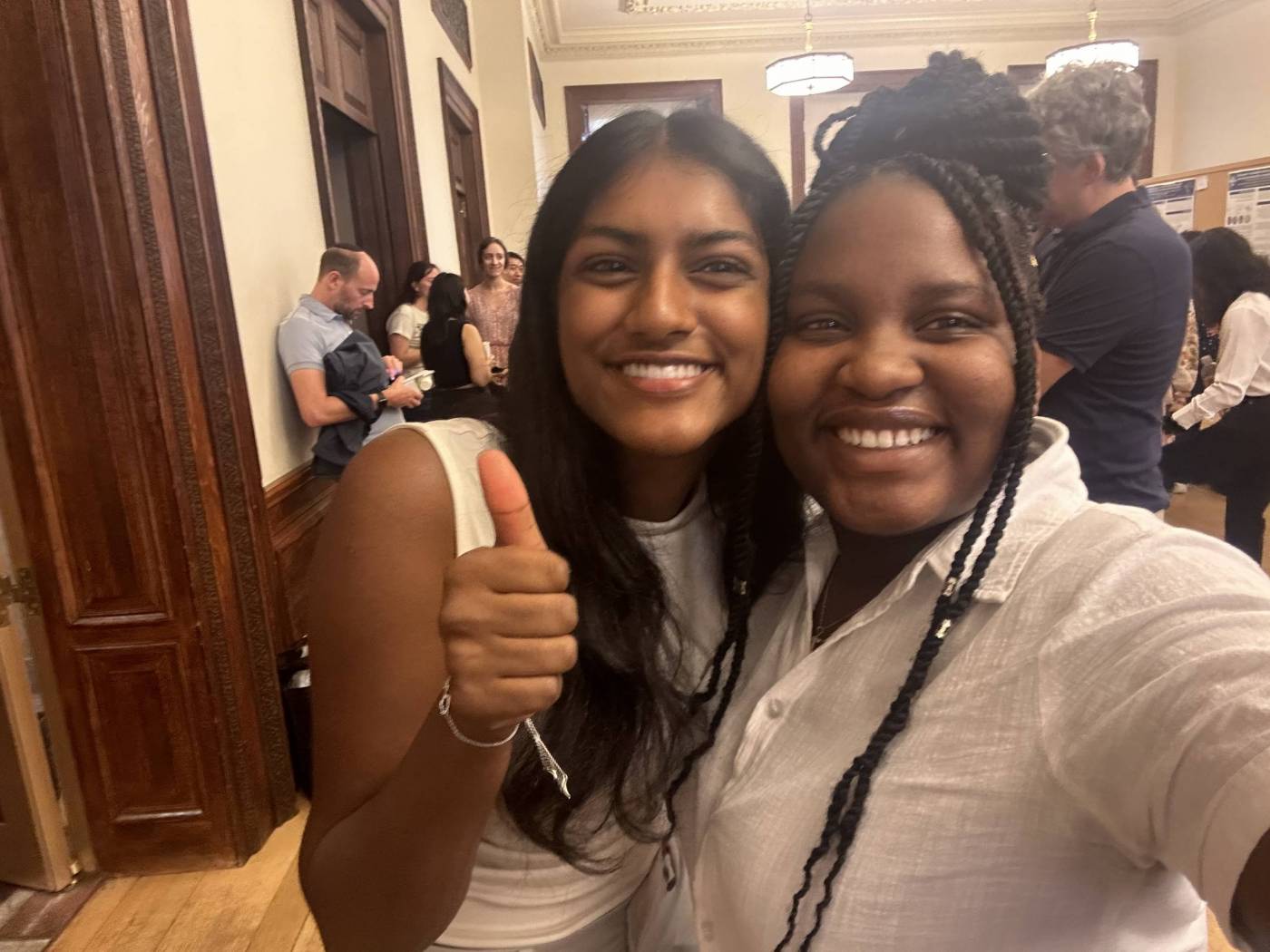 Two high-school aged girls posing for a selfie in a presentation hall. 